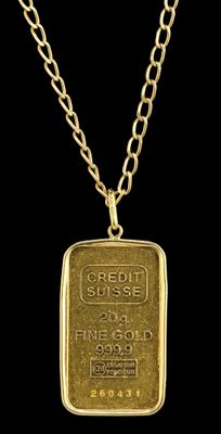 a gold bar pendant with a chain on a black background