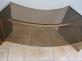 a glass table with a curved glass top on a tiled floor