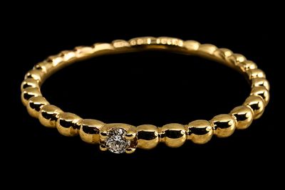 un gros plan d'une bague en or et diamants sur fond noir