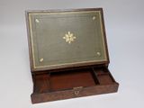 an old wooden box with a green cover and gold trim
