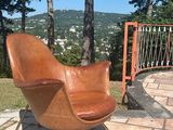 une chaise marron posée sur une terrasse en briques, près d'une clôture