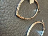 two gold hoop earrings on a brown leather surface