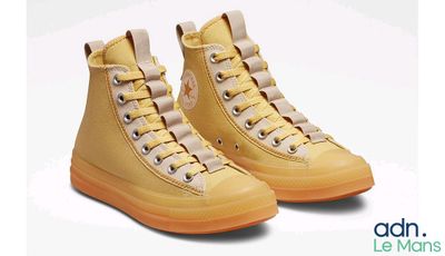 Des Converse jaunes à semelles orange sur fond blanc