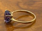 an image of a gold ring with a purple stone on a wooden table