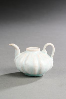 une théière blanche posée sur une table, sur fond gris