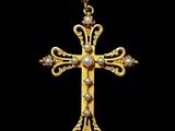 a gold cross pendant with pearls on a black background