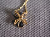 a close up of a gold necklace with a bow on it