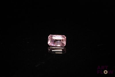 a close up of a pink diamond on a black surface