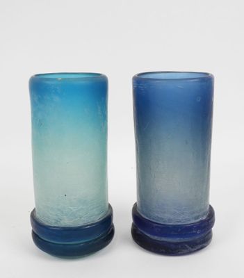 deux vases en verre bleu posés l'un à côté de l'autre sur une surface blanche