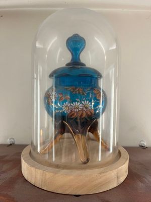 a glass bellow with a wooden base on a shelf