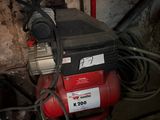 an image of a red air compressor in a dirty room