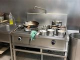 une cuisine avec une cuisinière et une casserole posée sur le plan de travail