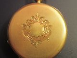 a gold pocket watch with a red string around it
