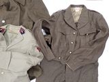 three military uniforms are laid out on a white surface
