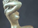 statue of a woman sitting on a rock with her hands on her head