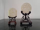 two small carved objects sitting on a black table