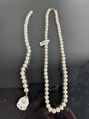 a close up of a white pearl necklace with a tag on it