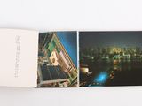 a hand holding an open book with a picture of a city in the background