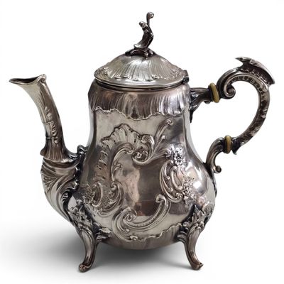 an antique silver tea pot with a bird on top