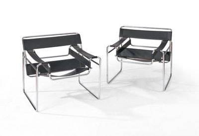 une paire de chaises en cuir noir et chrome sur fond blanc