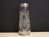 un vase en verre transparent avec un couvercle en argent posé sur une table