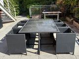 une table et des chaises sur une terrasse, avec un escalier en arrière-plan