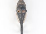 un masque africain accroché à un mur sur fond blanc