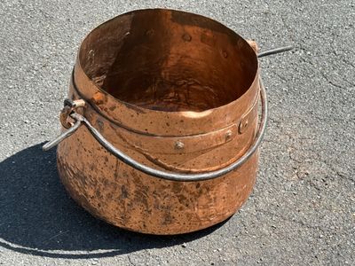 un grand seau en cuivre posé par terre