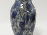 a blue vase with blue flowers on it on a white surface