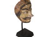 a close up of a wooden mask on a stand on a white background