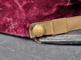 a close up of a red velvet hat with a gold buckle