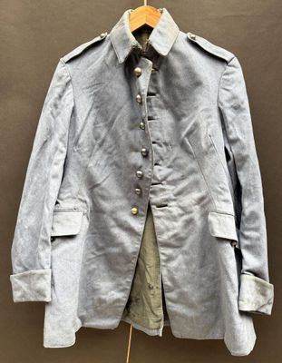 an old blue jacket is hanging on a hanger in front of a brown wall