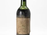 une vieille bouteille de vin posée sur une surface blanche