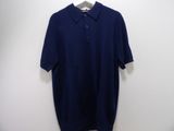 a blue polo shirt hanging on a hanger against a wall