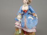 figurine of a woman in a blue dress sitting on a rock