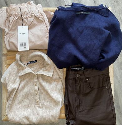 trois paires de pantalons, un pull et une chemise sont posés sur une chaise