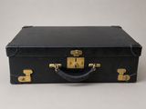 une vieille valise noire posée sur une table blanche