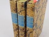 trois livres sont empilés sur une surface blanche