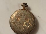 a small gold pocket watch sitting on a marble surface