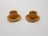 pair of yellow ceramic cups and saucers on a white surface