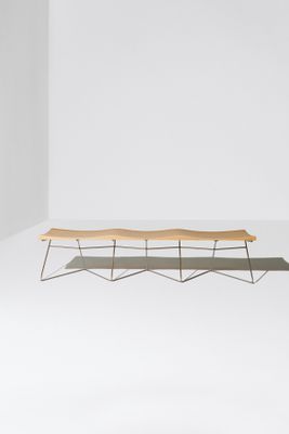 un banc en bois posé sur un sol blanc, près d'un mur