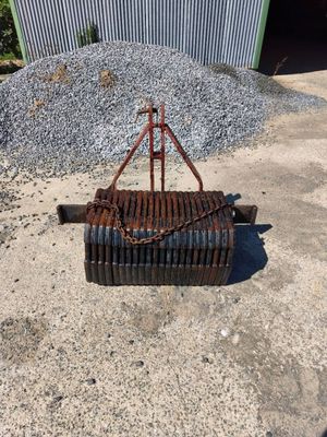 a rusted rake on the ground next to a pile of gravel