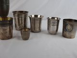 six silver cups and a vase are sitting on a table