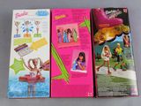two boxes of barbie dolls sitting on top of a table