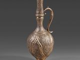 un vieux vase en argent muni d'une anse, sur un fond gris