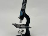 Gros plan sur un microscope posé sur une surface blanche, avec un fond blanc