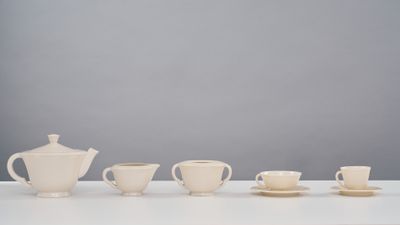 several cups and saucers are lined up on a white table