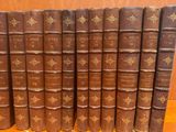 several old books are lined up on a shelf in a library