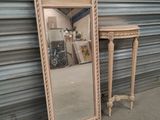 a mirror and a small table in front of a wall