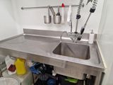 a sink with a metal counter top in a kitchen